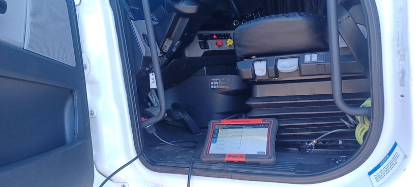 A diagnostic scanner plugged in on the floor of a truck cab